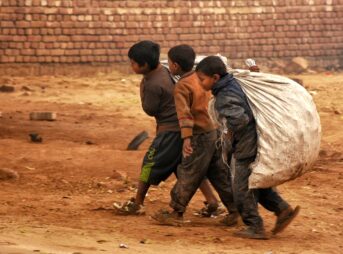 a group of young boys walking down a dirt road
